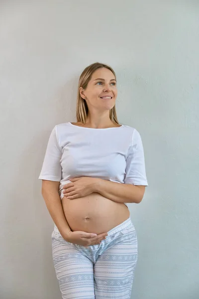 Vacker Gravid Kvinna Pyjamas Står Mot Bakgrund Vit Vägg Hemma — Stockfoto