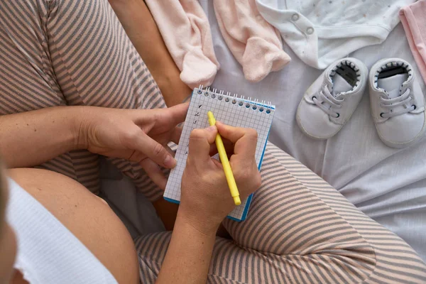 Top View Pregnant Woman Bed Preparing Baby Clothes Home Writing — Stock Photo, Image