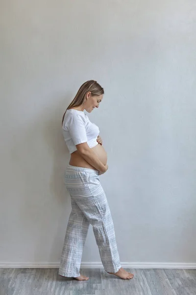 Vacker Gravid Kvinna Pyjamas Står Mot Bakgrund Vit Vägg Hemma — Stockfoto