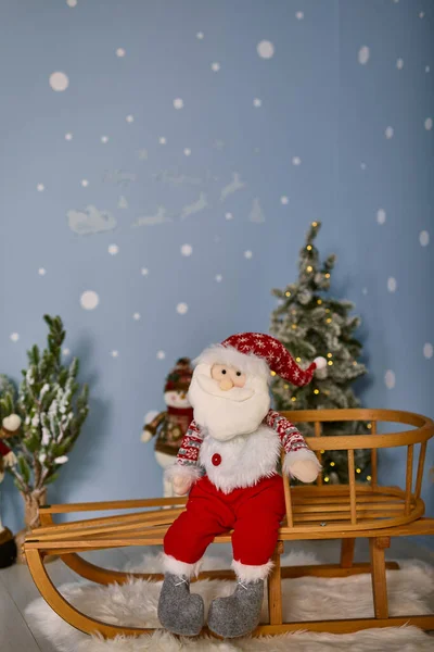 Leksak Jultomten Sitter Träsläde Bakgrunden Blå Vägg Dekorerad För Jul — Stockfoto