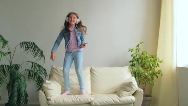 Funny Happy Little Girl Headphone Yang Jumping Couch Home Putri — Stok Video