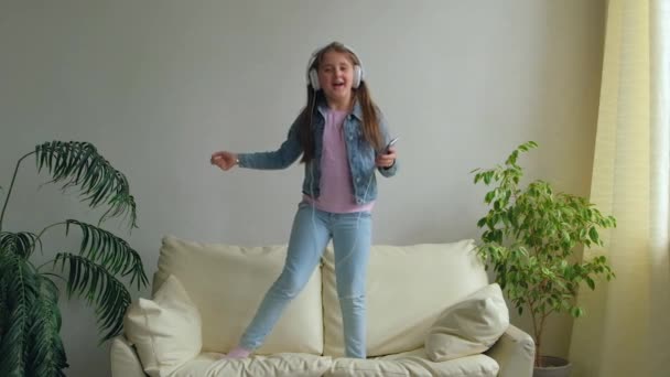 Funny Happy Little Girl Hovedtelefoner Hopper Sofaen Derhjemme Datter Leger – Stock-video