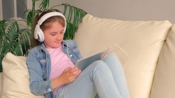 Barnet Hörlurarna Med Surfplattan Ung Flicka Liggande Soffa Lyssna Musik — Stockvideo