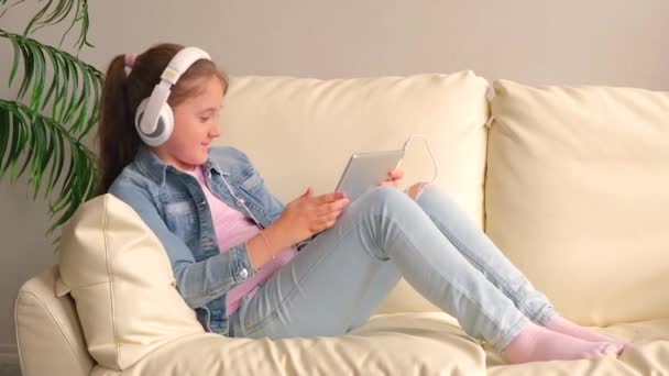 Linda Niña Con Ropa Casual Auriculares Usando Una Tableta Escuchando Videoclip