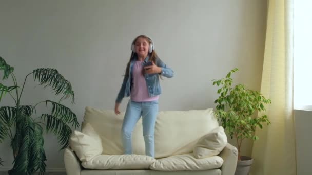 Funny Happy Little Girl Hovedtelefoner Hopper Sofaen Derhjemme Datter Leger – Stock-video