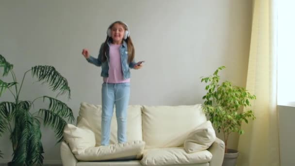Funny Happy Little Girl Hovedtelefoner Hopper Sofaen Derhjemme Datter Leger – Stock-video