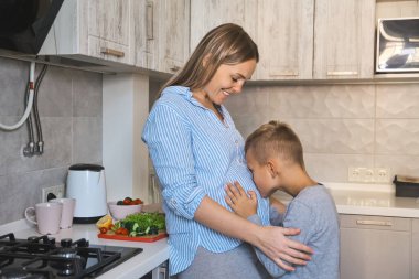 Hamile anne ve çocuk birlikte oynuyorlar ve mutfakta birbirlerine sarılıyorlar. Anne ve oğlu evde kahvaltı ederken iyi duygular paylaşıyorlar..