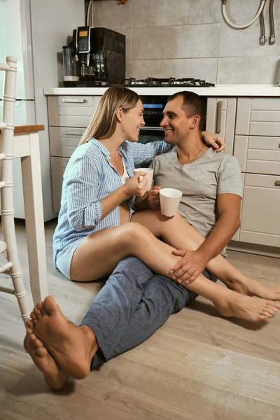 Young Pregnant Couple Kitchen Floor Hug Laugh Cups Tea Rejoicing — Stock Photo, Image