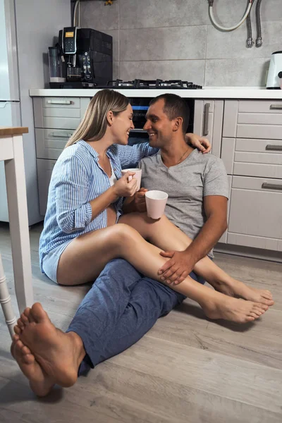 Young Pregnant Couple Kitchen Floor Hug Laugh Cups Tea Rejoicing — Stock Photo, Image