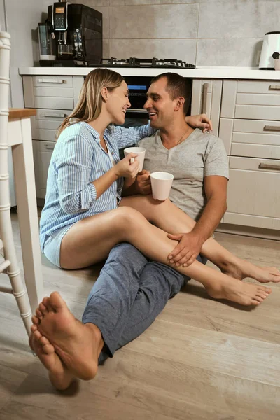 Young Pregnant Couple Kitchen Floor Hug Laugh Cups Tea Rejoicing — Stock Photo, Image