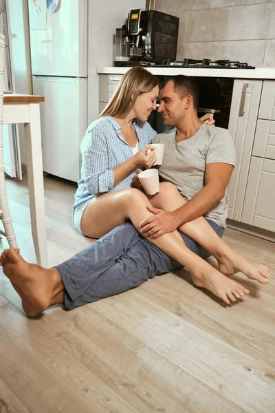 Young Pregnant Couple Kitchen Floor Hug Laugh Cups Tea Rejoicing — Stock Photo, Image