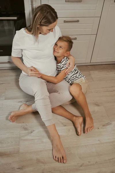 아이가 임산부가 부엌에서 포옹하고 집에서 식사를 하면서 감정을 나누는 어머니 — 스톡 사진