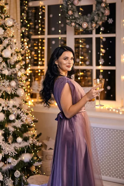 Parti, içkiler, tatiller, insanlar ve kutlama konsepti. Bir bardak köpüklü şarap ve şampanyayla gülümseyen güzel elbiseli kadın..