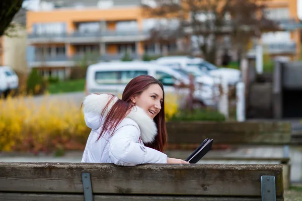 Jonge vrouw zitten op een bankje met een tablet — Stockfoto