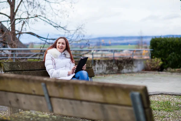 타블렛와 공원 벤치에 앉아 젊은 여자 — 스톡 사진