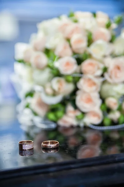 Wedding rings and bouquet on the table — Stock Photo, Image