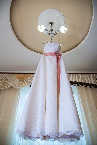 Свадебное платье висит на люстре в комнате — стоковое фото