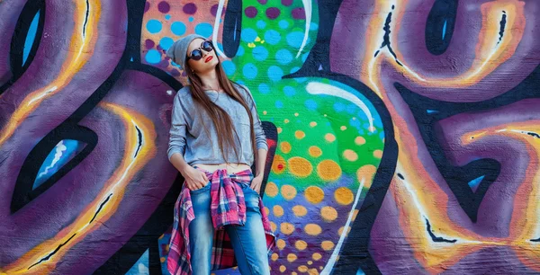 Hermosa chica fresca en sombrero y gafas de sol sobre la pared de graffiti —  Fotos de Stock