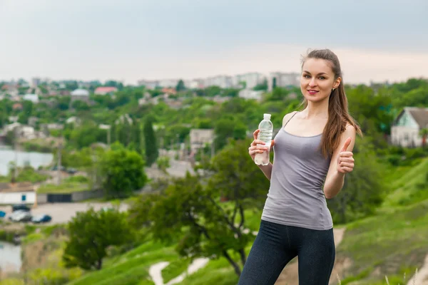 Thirsty fitness girl holding bottle of water