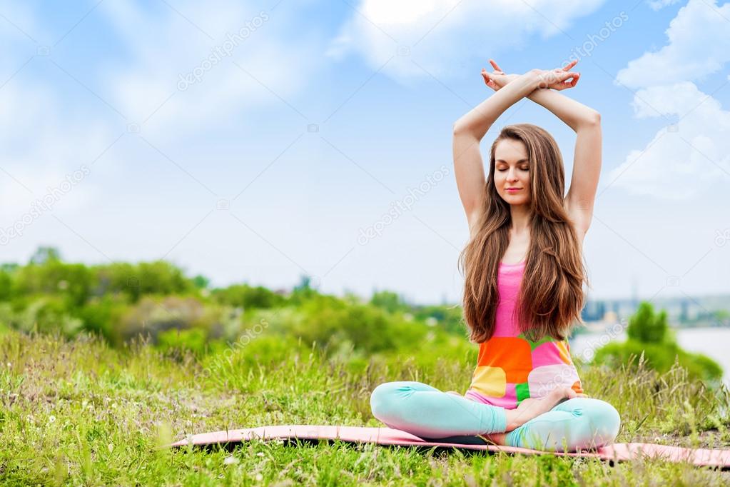 Pretty woman doing yoga exercises on nature landscape