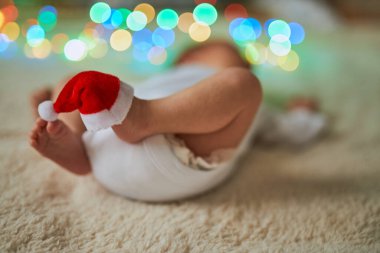 Bir tanesinin ayak parmaklarında minyatür kırmızı bir Noel Baba şapkası olan küçük ayakları havada sırt üstü yatan yeni doğmuş bir bebeğin yakın plan fotoğrafı..