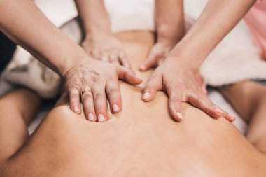 Aynı anda dört elle sırt masajı. İki profesyonel masör hastayı tedavi ediyor.