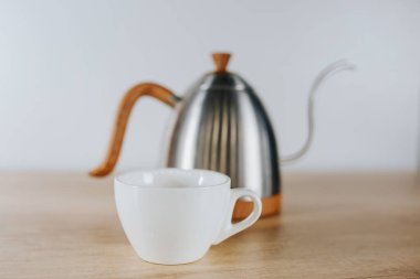 Kahve metali çaydanlık ve beyaz bardak ön planda - kahve tabakları