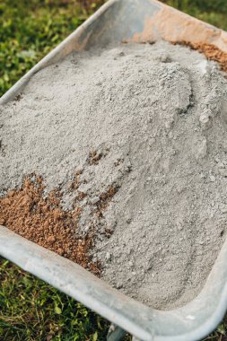 İnşaat işçisi beton-kum harcı hazırlıyor asfalt döşemek için - inşaat el arabası iş için