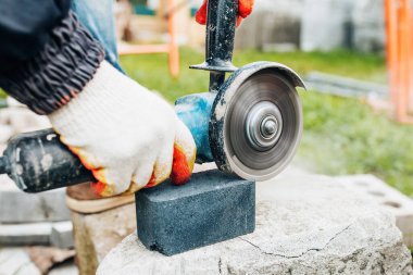 Ellerinde öğütücü, tozlu elmas bir disk, kaldırım taşlarını kesiyor. Profesyonel döşeme döşemeleri.