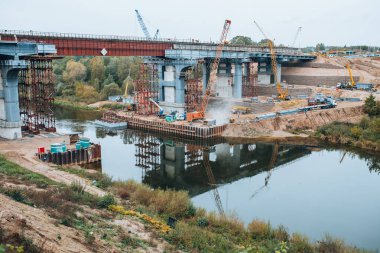 Minsk, Belarus - 20 Ekim 2020: Nehir kıyısındaki yüksek bankalar ve ağır inşaat ekipmanları arasında bir karayolu ve demiryolu köprüsü inşaatı