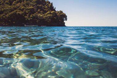 Dağdan mavi deniz lagünü manzarası. Yoğun yaprak döken ormanlarla kayalık kıyı.