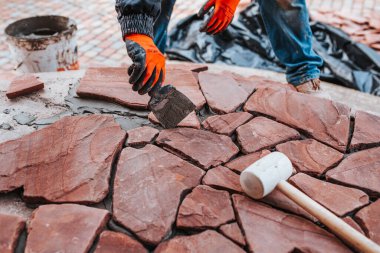 Usta tiler, doğal taş kiremitlerin eklemlerini tutkalla doldurur - evin dış kısmı.
