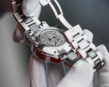  Beyaz eldivenli bir satıcı pahalı bir İsviçre saati gösteriyor Longines - bayram hediyesi olarak bir erkek bilek kronometresi