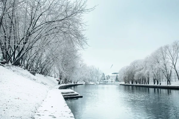 Winter in the city - snow on the banks of the river and on the trees covered with frost