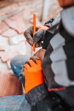 Bir tiler, doğal taşla çevrili bir kalemle kesmek için taşı işaretler.