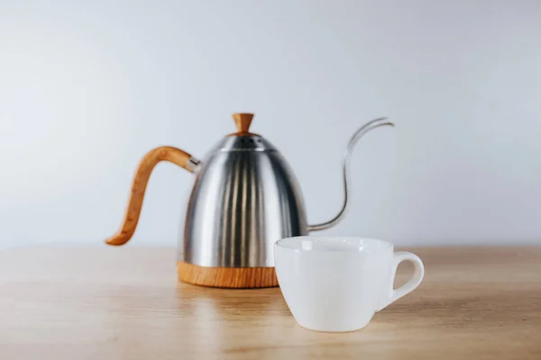 木桌上有薄茶壶和白色瓷杯的咖啡金属茶壶 — 图库照片