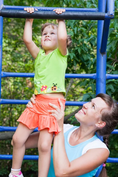 Chica cuelga en barra horizontal con madre — Foto de Stock