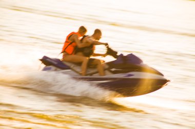 Young couple drive on jet ski clipart