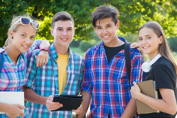 Giovani amici studenti con libri e gadget — Foto Stock