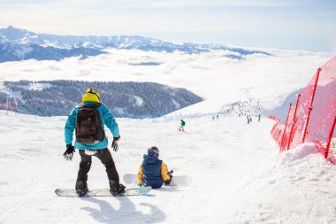 Bir kayak merkezinde kayak yapmaya hazırlanan bir çift genç kayakçı.