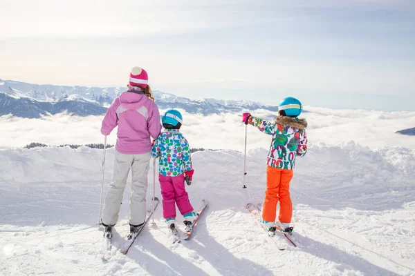 带着两个孩子在滑雪胜地滑雪的年轻女子 — 图库照片