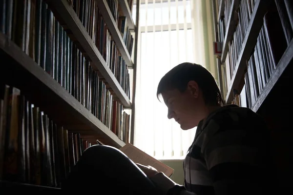 少年学生は図書館で本を読む — ストック写真