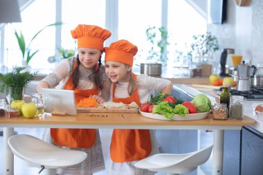 Evdeki mutfakta yemek yapan iki küçük kız.