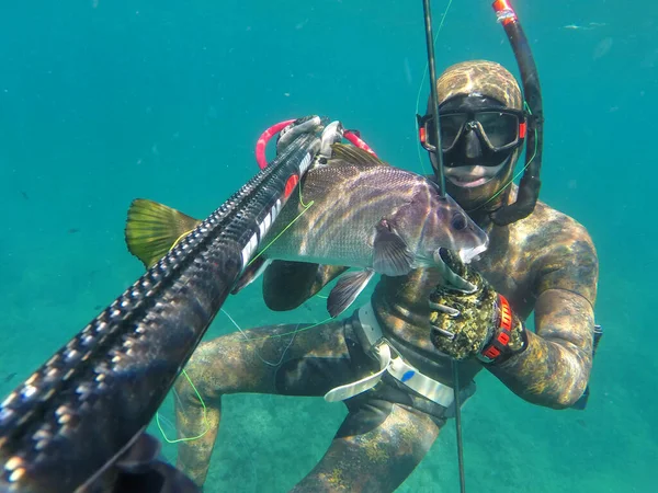spearfisher swims on the surface of the sea after diving with fish