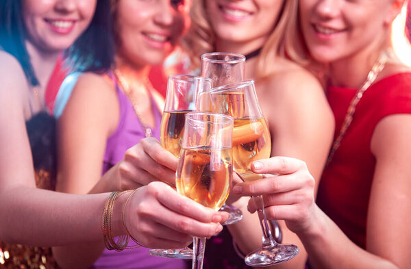 Beautiful girls clink glasses of champagne at a party