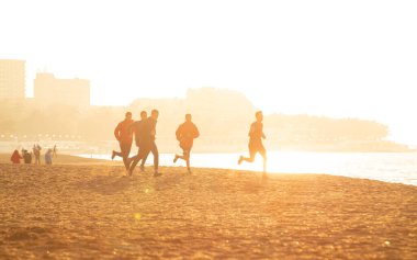 bir grup genç insan kumsalda güzel yaz günbatımı üzerinde çalışır.