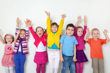 Elleri beyaz duvarda olan büyük bir grup çocuk.
