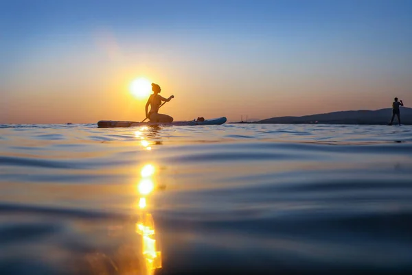 Genç Kız Gün Batımında Denizde Sörf Yapmaya Devam Ediyor — Stok fotoğraf