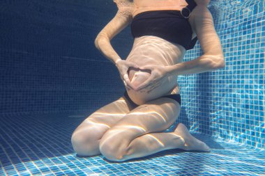 Hamile kadın mavi su havuzunda dinleniyor. Tanımlanamayan vücut. 