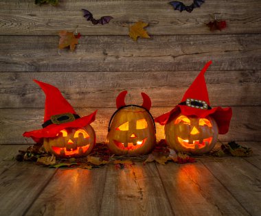 Geceleri evdeki masada oyulmuş yüzleri olan üç balkabağı.